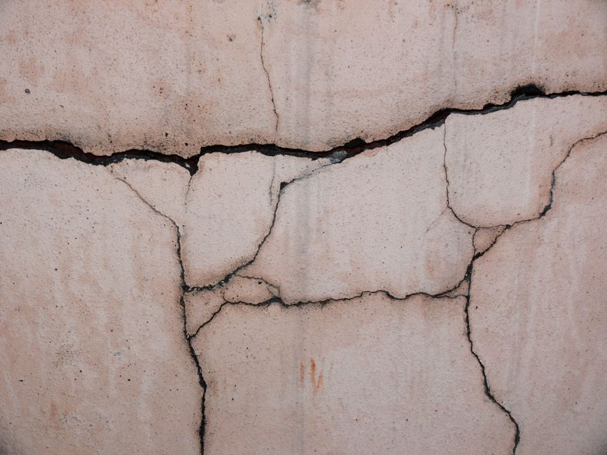 Close-up of a cracked concrete wall, showcasing its unique texture and patterns.